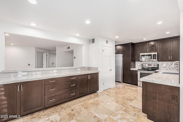 6119 E Sandra Ter, Scottsdale, AZ 85254 - kitchen featuring stainless steel appliances, a sink, dark brown cabinets, light countertops, and recessed lighting
