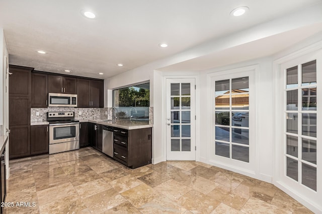 6119 E Sandra Ter, Scottsdale, AZ 85254 - kitchen with stainless steel appliances, dark brown cabinetry, decorative backsplash, light countertops, and recessed lighting