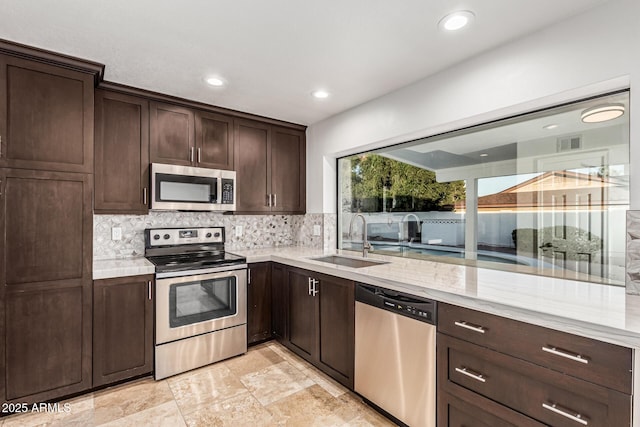 6119 E Sandra Ter, Scottsdale, AZ 85254 - kitchen featuring appliances with stainless steel finishes, a sink, dark brown cabinets, tasteful backsplash, and recessed lighting