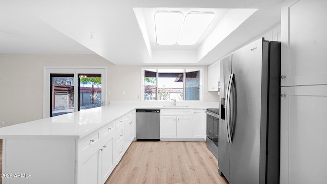 kitchen featuring appliances with stainless steel finishes, light countertops, a peninsula, and white cabinetry