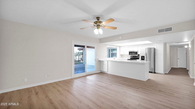 kitchen featuring stainless steel appliances, light countertops, visible vents, white cabinets, and a peninsula