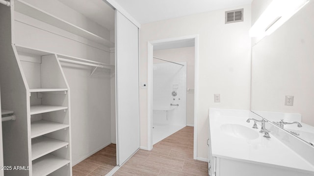 full bathroom with a spacious closet, wood finished floors, vanity, and visible vents