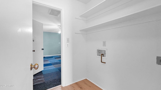 clothes washing area with washer hookup, visible vents, wood finished floors, laundry area, and baseboards