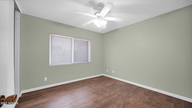 unfurnished room featuring dark wood-style flooring, a ceiling fan, and baseboards