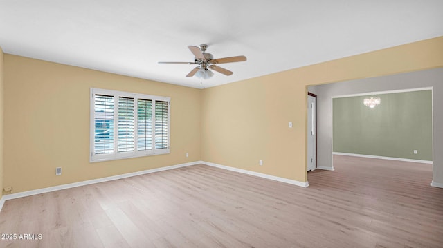 unfurnished room featuring light wood finished floors, baseboards, and ceiling fan with notable chandelier