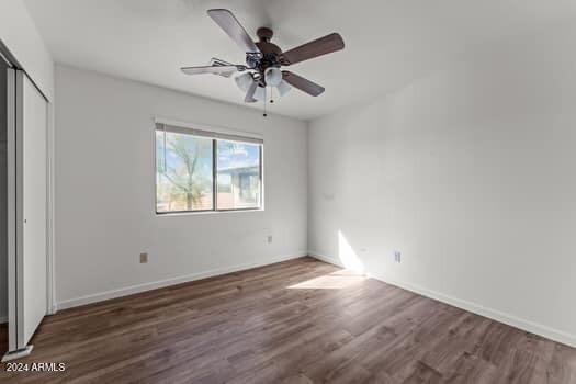 unfurnished bedroom with dark wood-type flooring, a closet, and ceiling fan