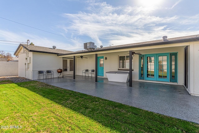 rear view of house with a lawn, a patio area, central air condition unit, and french doors