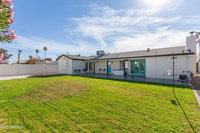 rear view of property with french doors, a patio, and a lawn