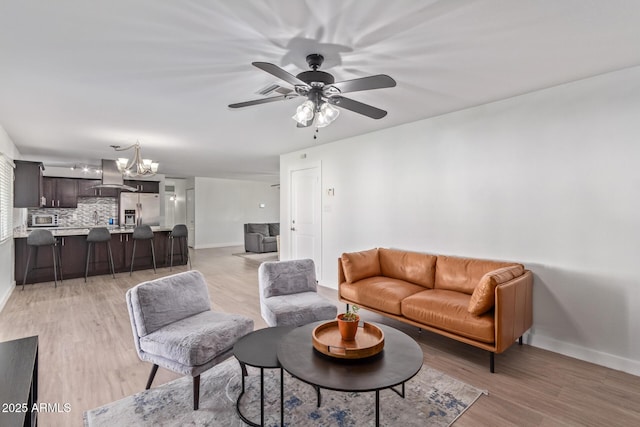 living room with ceiling fan with notable chandelier and light wood-type flooring