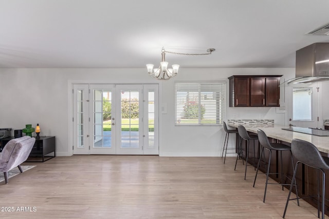 kitchen with light stone countertops, a notable chandelier, decorative light fixtures, black electric cooktop, and a breakfast bar