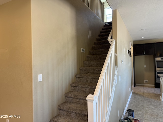 staircase with tile patterned floors and baseboards