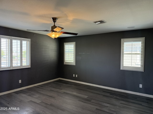 unfurnished room with wood finished floors, baseboards, visible vents, and plenty of natural light