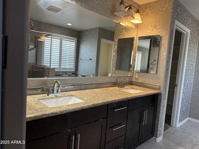 full bathroom featuring baseboards, visible vents, a sink, and wallpapered walls
