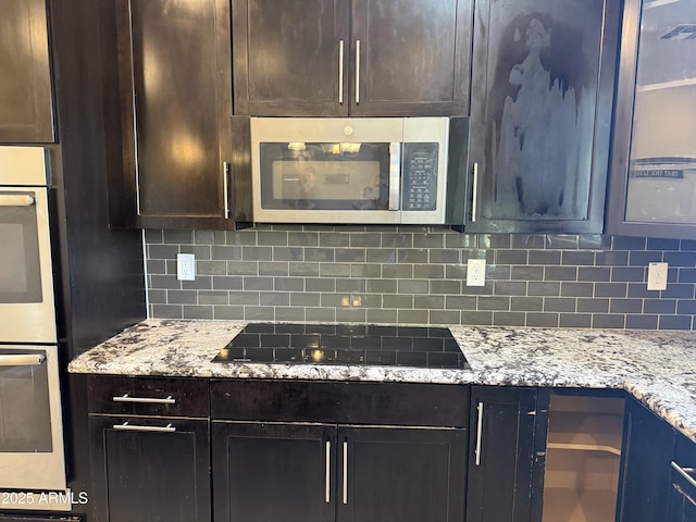 kitchen featuring light stone counters, decorative backsplash, dark brown cabinets, and stainless steel appliances