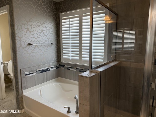 full bathroom featuring toilet, tile patterned floors, wallpapered walls, and a garden tub