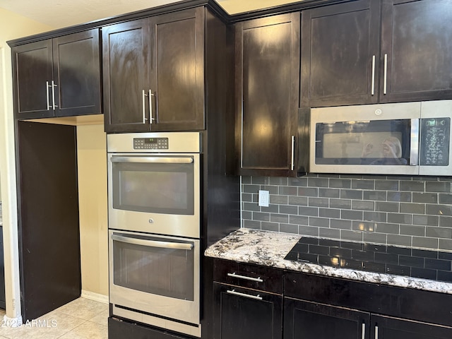 kitchen with light tile patterned floors, backsplash, dark brown cabinets, light stone countertops, and appliances with stainless steel finishes