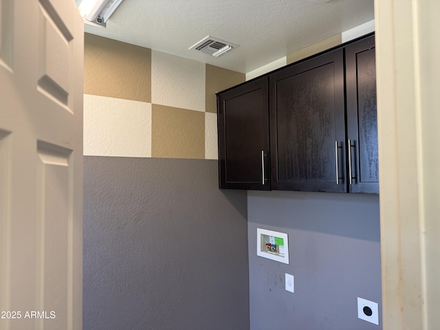 clothes washing area featuring visible vents, washer hookup, a textured wall, cabinet space, and electric dryer hookup