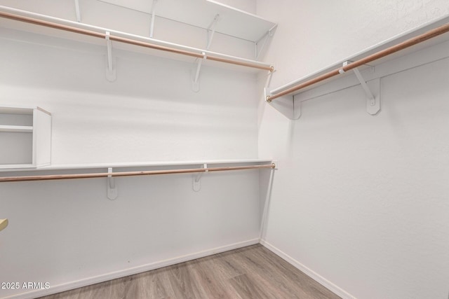 walk in closet with light hardwood / wood-style flooring