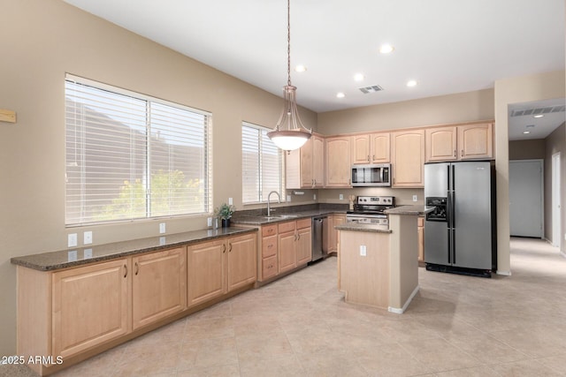 kitchen featuring stainless steel appliances, sink, a center island, dark stone countertops, and hanging light fixtures