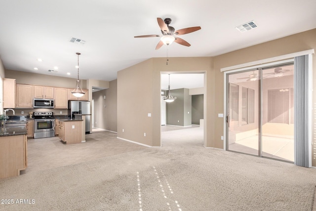 kitchen with light brown cabinets, a center island, hanging light fixtures, and appliances with stainless steel finishes