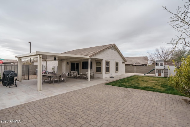 rear view of property featuring a playground, a lawn, and a patio area