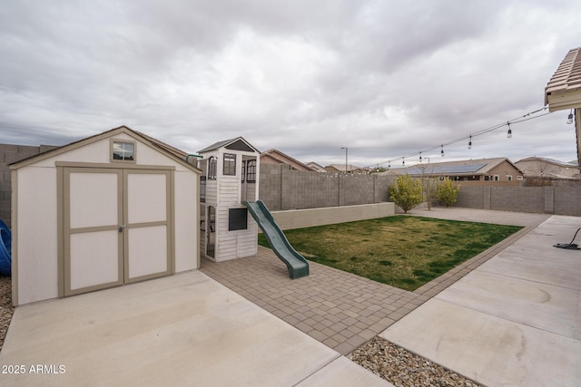view of yard featuring a playground, a shed, and a patio area