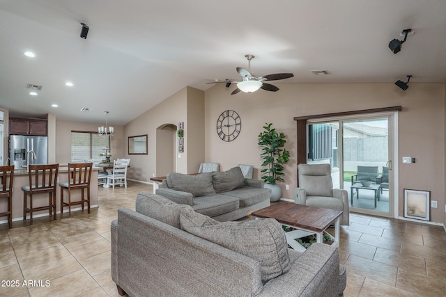 living room featuring lofted ceiling, ceiling fan with notable chandelier, and a wealth of natural light