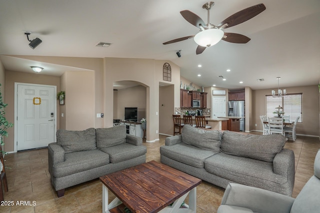 living room with ceiling fan with notable chandelier and vaulted ceiling