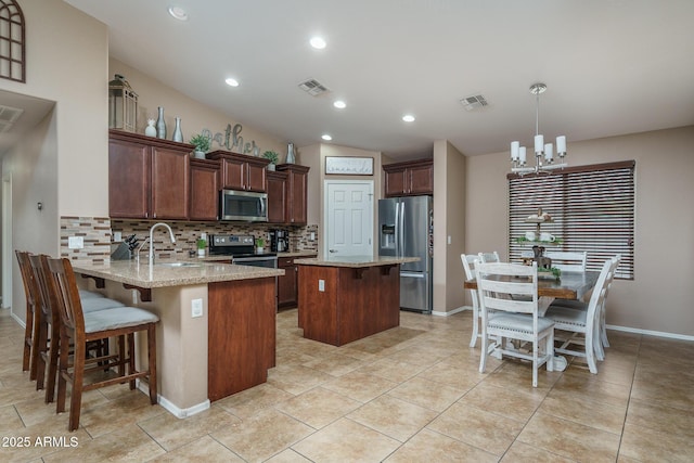 kitchen featuring appliances with stainless steel finishes, tasteful backsplash, sink, light stone counters, and kitchen peninsula