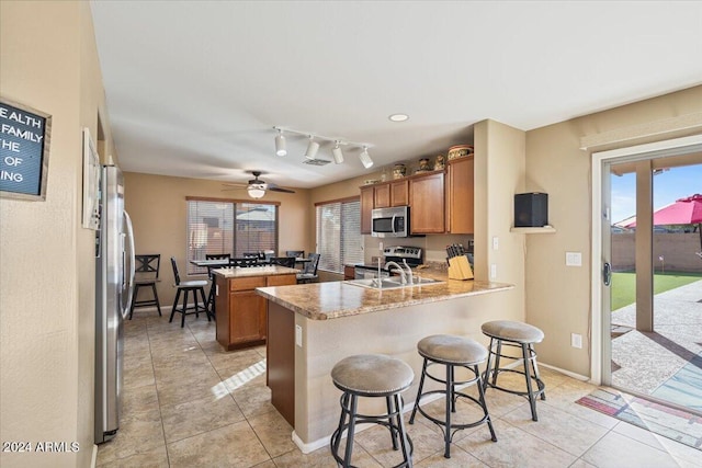 kitchen featuring kitchen peninsula, appliances with stainless steel finishes, a kitchen breakfast bar, and a healthy amount of sunlight