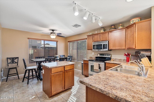 kitchen featuring ceiling fan, sink, light tile patterned floors, a kitchen island, and appliances with stainless steel finishes