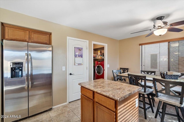 kitchen featuring ceiling fan, stainless steel fridge, light tile patterned floors, a kitchen island, and washer / clothes dryer