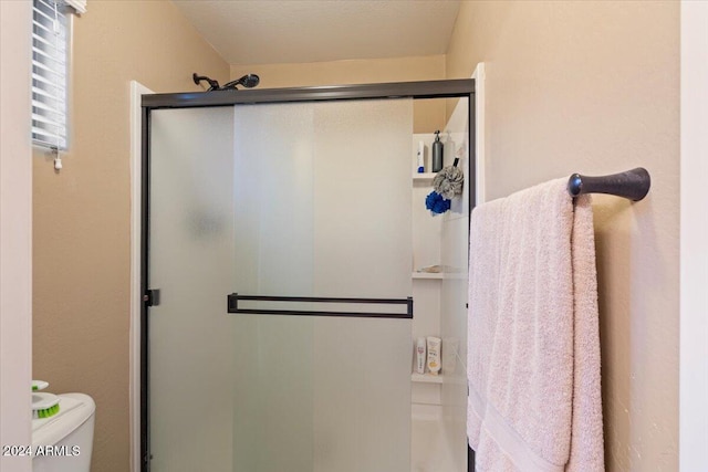 bathroom with a shower with door and toilet