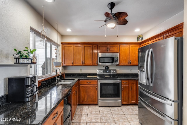 7210 W Caron Dr, Peoria, AZ 85345 - kitchen with stainless steel appliances, a sink, brown cabinetry, ceiling fan, and a textured wall
