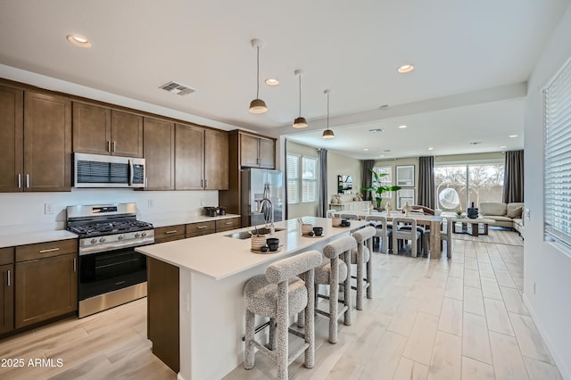 10105 E Ulysses Ave, Mesa, AZ 85212 - kitchen with appliances with stainless steel finishes, dark brown cabinetry, an island with sink, a breakfast bar, and recessed lighting