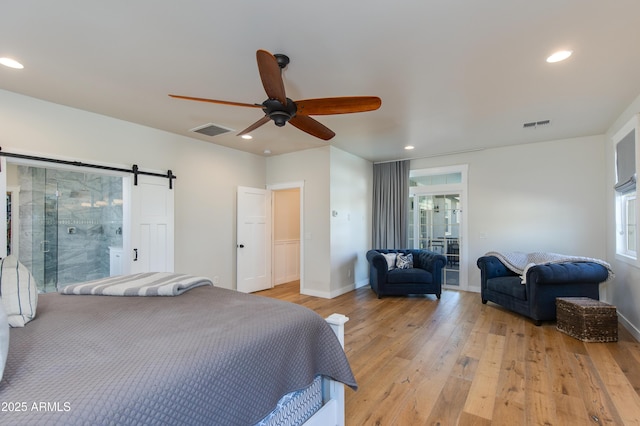 bedroom featuring ceiling fan, a barn door, and light hardwood / wood-style floors