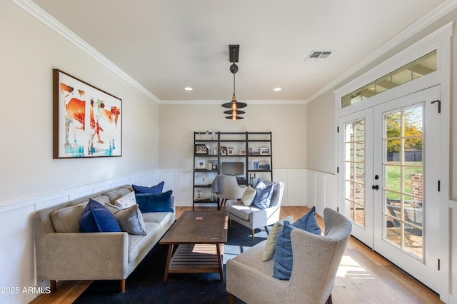 living room with french doors, crown molding, and light hardwood / wood-style floors