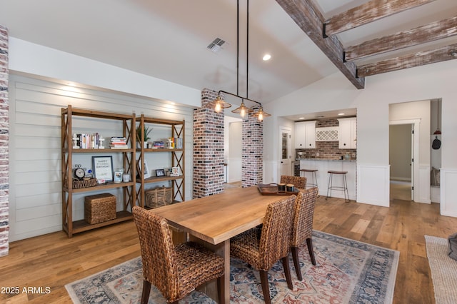 dining area featuring vaulted ceiling with beams and light hardwood / wood-style flooring