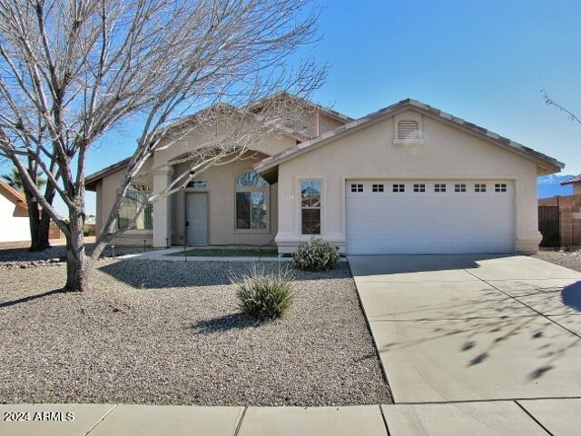 view of front of property featuring a garage, concrete driveway, and stucco siding