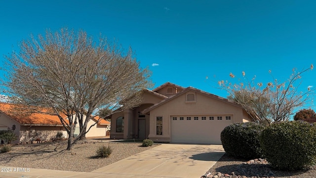 view of front of property featuring an attached garage, driveway, a tiled roof, and stucco siding