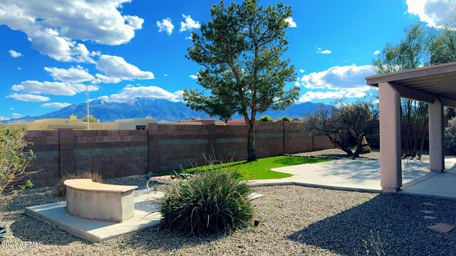 view of yard featuring a fenced backyard, a mountain view, and a patio