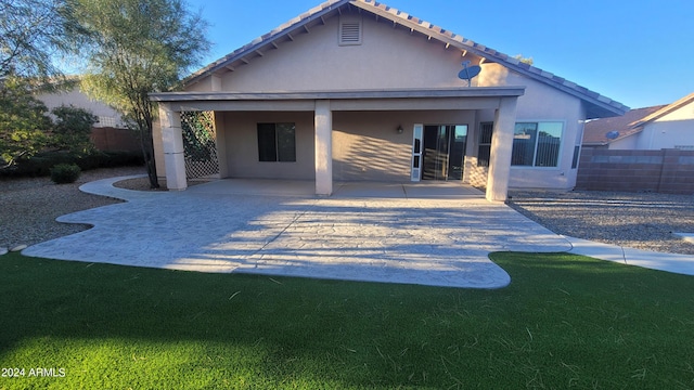 back of property with a lawn, fence, a patio, and stucco siding