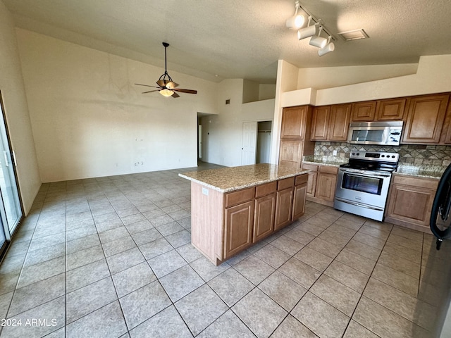 kitchen featuring stainless steel appliances, tasteful backsplash, a kitchen island, vaulted ceiling, and ceiling fan