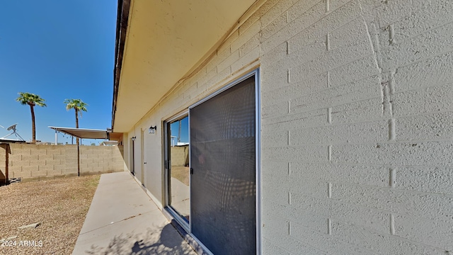 view of side of home featuring concrete block siding and fence