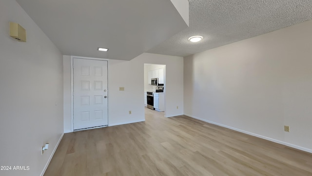 spare room featuring a textured ceiling, baseboards, and light wood-style floors