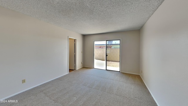 empty room featuring baseboards, a textured ceiling, and light colored carpet