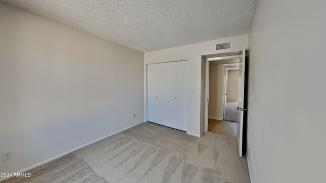 unfurnished bedroom with a textured ceiling, baseboards, visible vents, and light colored carpet