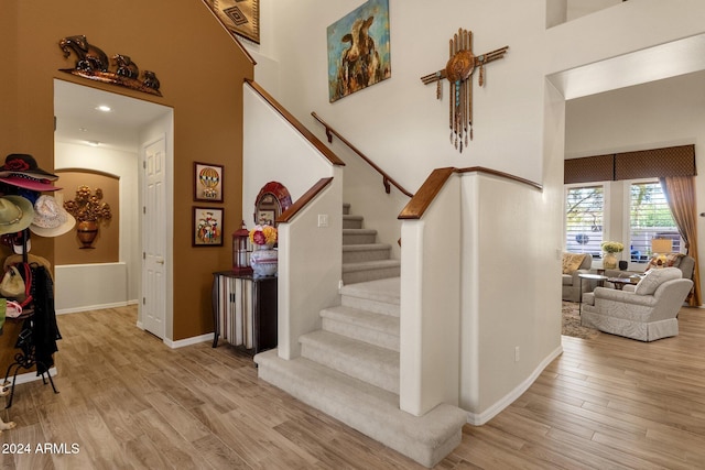 stairs with a towering ceiling and hardwood / wood-style flooring