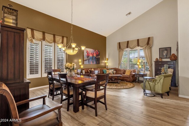 dining area featuring high vaulted ceiling, a notable chandelier, and light wood-type flooring