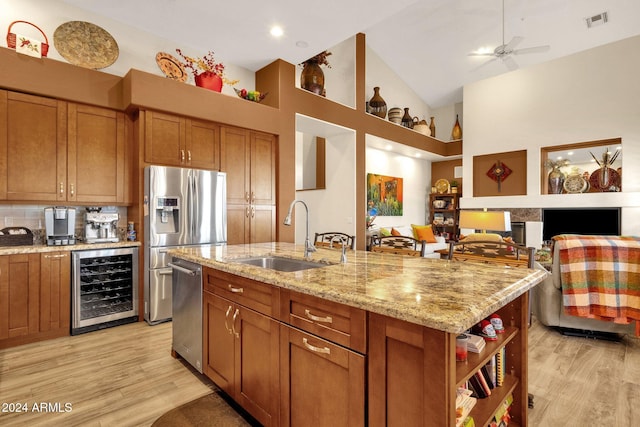 kitchen featuring light hardwood / wood-style floors, wine cooler, a center island with sink, sink, and high vaulted ceiling